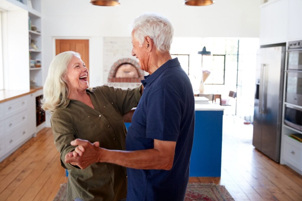 An older couple dancing together in their kitchen